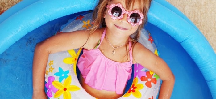 Young girl with sunglasses sitting back in an inflatable kiddie pool